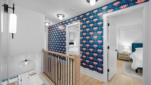 A modern hotel room with a wooden staircase, a large window, and a bathroom with a mirror and white fixtures. - Location! w/King Beds+Hot Tub+GameRoom+Theater+Gym+Fire Pit (Prairie Village)