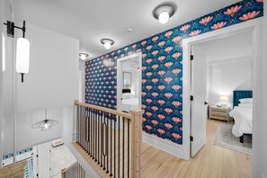 A modern hotel room with a wooden staircase, a large window, and a bathroom with a mirror and white fixtures. - Location! w/King Beds+Hot Tub+GameRoom+Theater+Gym+Fire Pit (Prairie Village)
