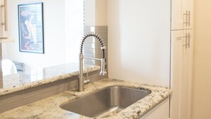 A kitchen with white cabinets, a stainless steel sink, and a granite countertop.