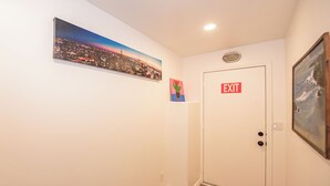 A hallway with an exit door, a cityscape painting, and a cactus painting on the wall. - Charming and spacious 3-bedroom HOUSE in a vibrant part of San Diego with AC. (San Diego)