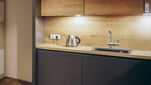A modern kitchen with a stainless steel kettle, a sink, and wooden cabinets. - Apartment fuer 2 Personen (Brixen im Thale)