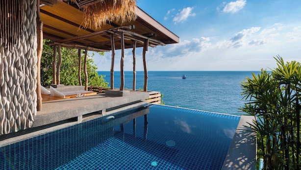 A infinity pool with a clear view of the ocean, a thatched roof structure, and a stone wall. - View Point Resort Koh Tao (Koh Tao)