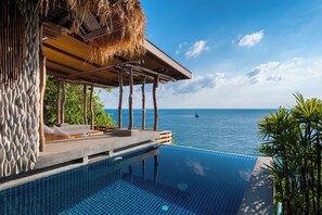 A infinity pool with a clear view of the ocean, a thatched roof structure, and a stone wall. - View Point Resort Koh Tao  (Koh Tao)