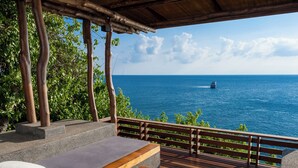 A wooden deck with outdoor seating, overlooking a clear blue sea and a boat in the distance. - View Point Resort Koh Tao (Koh Tao)