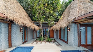 A pool area with two thatched-roof structures, a central pathway, and a small garden. - View Point Resort Koh Tao (Koh Tao)