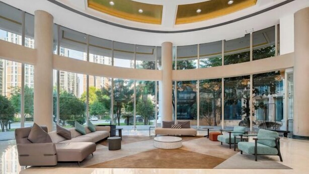 A spacious lobby with a curved ceiling, large windows, and a mix of seating areas including sofas and chairs.