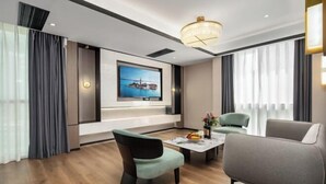 A modern living room with a flat-screen TV, comfortable seating, and a chandelier.