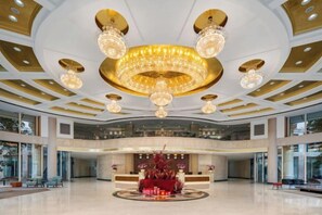 A spacious lobby with a grand chandelier, a reception desk, and a large window. - Jinxin Huayuan Hotel (Shantou)