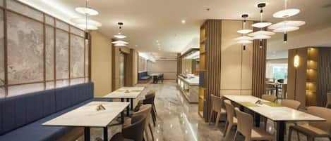 A restaurant interior with booths, tables, and hanging pendant lights.