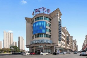 A multi-story building with a prominent sign at the top. - Jinxin Huayuan Hotel (Shantou)