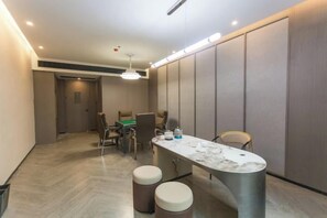 A modern hotel room with a dining area, a marble table, and a sofa. - Jinxin Huayuan Hotel (Shantou)