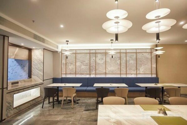A modern dining area with tables, chairs, and a large window with a view. - Jinxin Huayuan Hotel (Shantou)