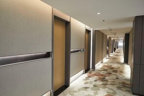 A hotel corridor with doors on both sides, a patterned floor, and recessed lighting. - Jinxin Huayuan Hotel (Shantou)