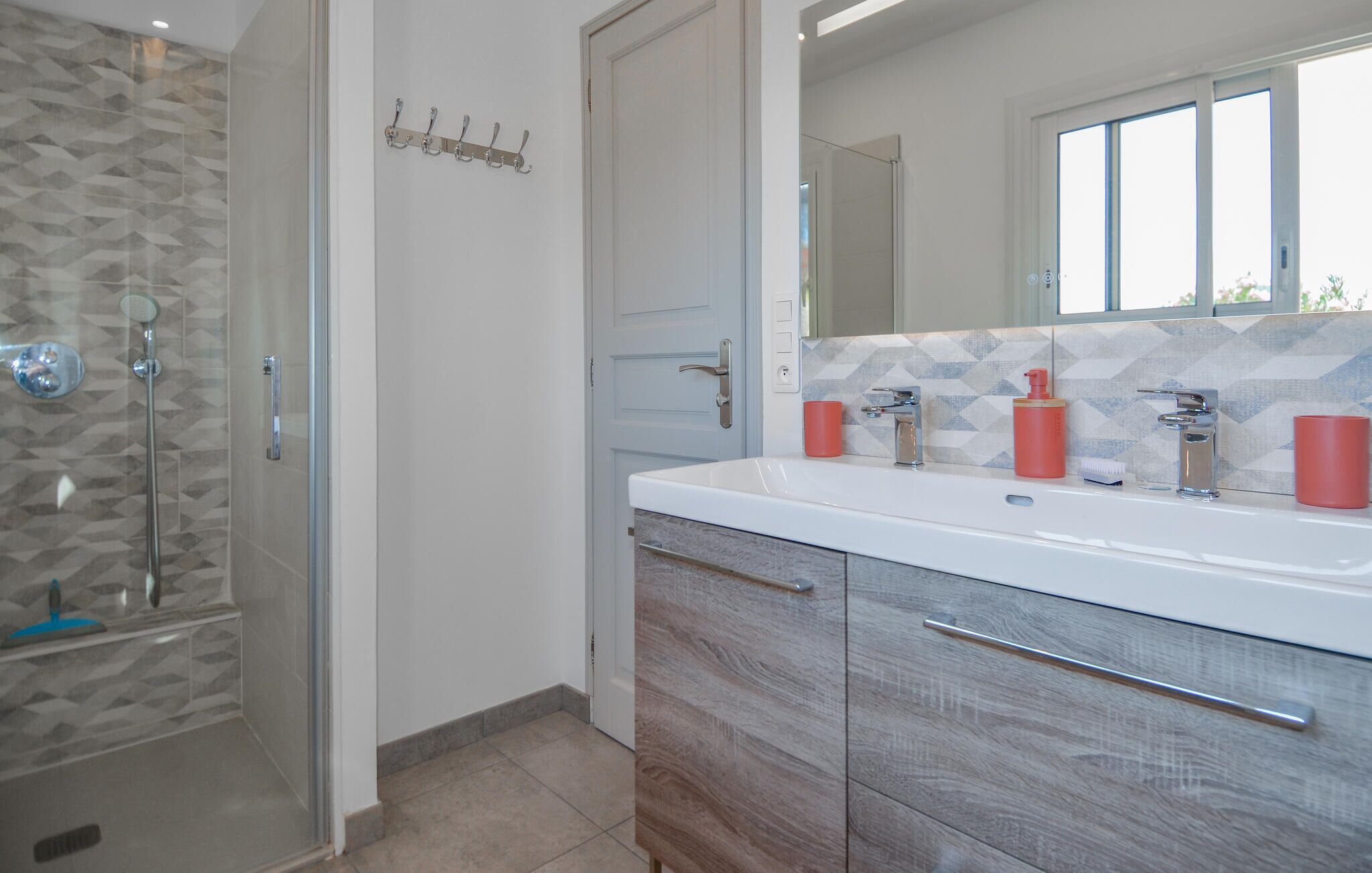 Une salle de bain moderne avec une douche, un meuble-lavabo avec un miroir et un pare-feu en carreaux.