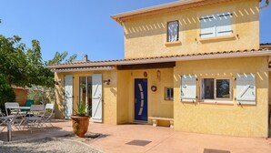 A two-story building with a yellow exterior, a blue door, and a patio area with outdoor furniture. - Cozy home in Marguerittes (Marguerittes)