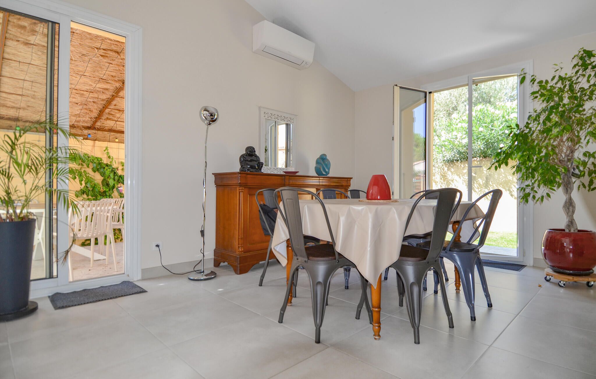A dining area with a table and chairs, a wooden cabinet, and a potted plant.