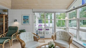 A sunlit room with wicker furniture, a painting, and a view of an outdoor patio.