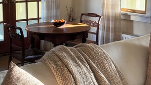 A cozy living room with a round wooden table, two chairs, a sofa with a knitted throw, and a door with glass panels. - HollyKissHudsonValley Renovated 1900 Lodge, Full House. (Catskill)