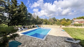 A rectangular swimming pool with a stone deck, surrounded by lounge chairs and a stone wall. - Awesome apartment in Medulin with WiFi (Medulin)