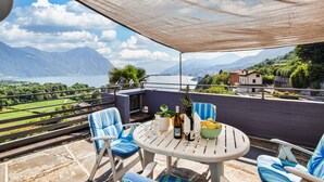 Ein Balkon mit Tisch, Stühlen und Blick auf einen See und Berge.