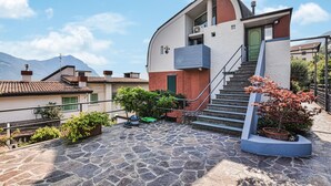 Ein modernes Haus mit einer Steinterrasse, einer grünen Tür und einer Treppe, die zu der oberen Etage führt.