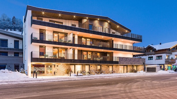 A multi-story hotel with balconies, a stone facade, and a snow-covered ground. - Amazing apartment in Brixen im Thale (Brixen im Thale)
