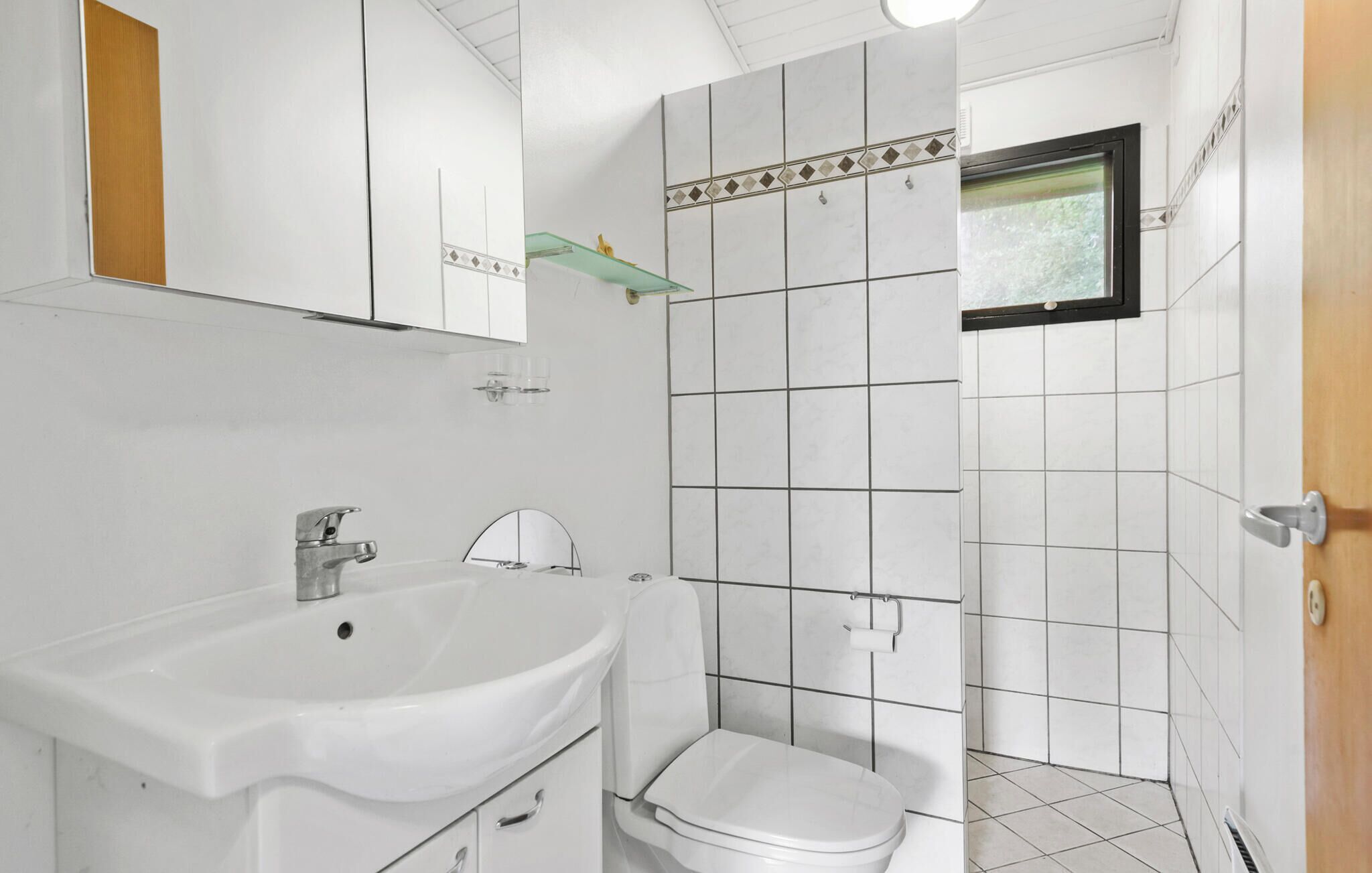 Ein Badezimmer mit einem weißen Waschbecken, einer Toilette und einem kleinen Fenster.