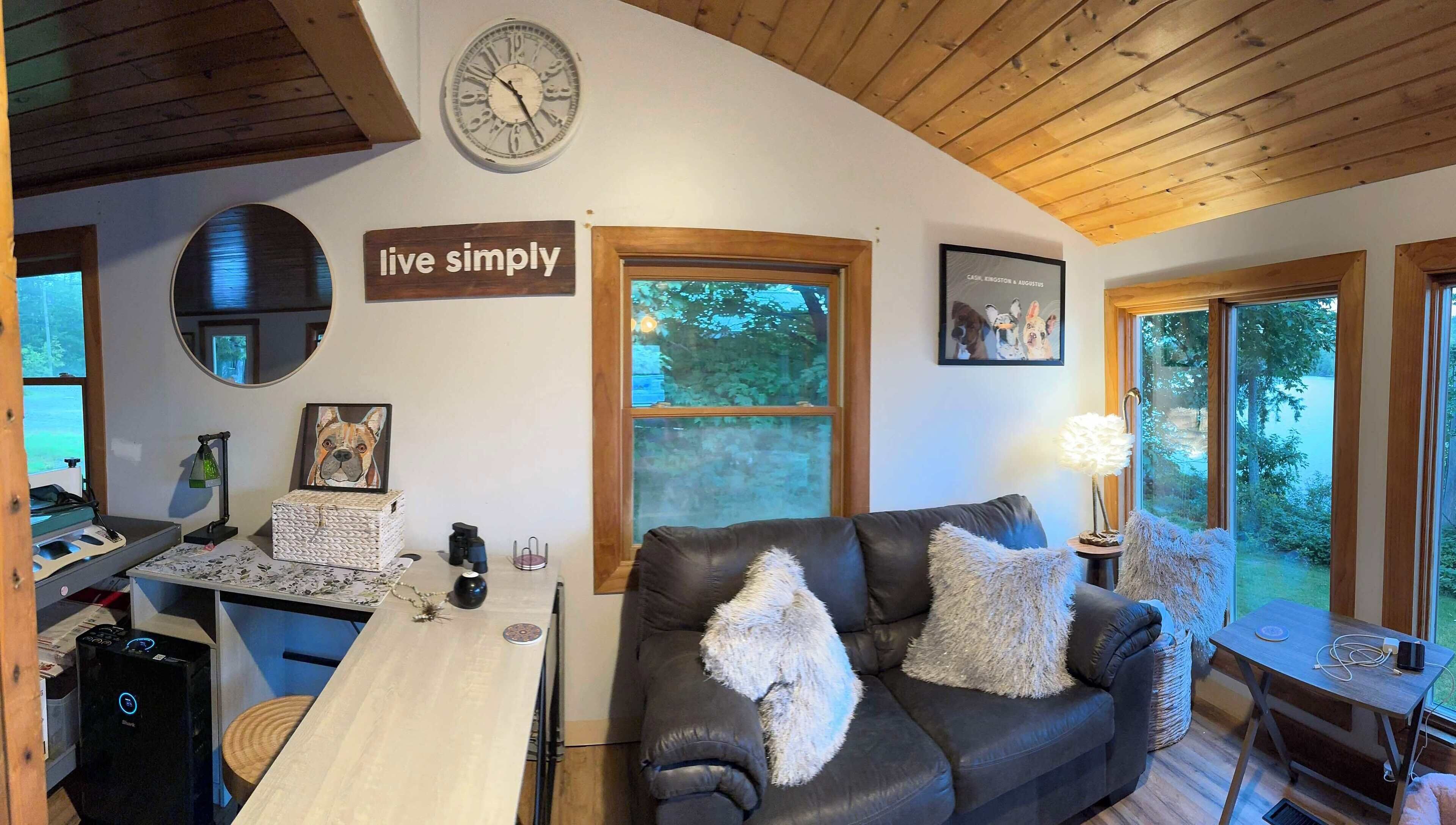Una sala de estar acogedora con un sofá de cuero, una mesa de madera y un cartel que dice 'vive simplemente'.