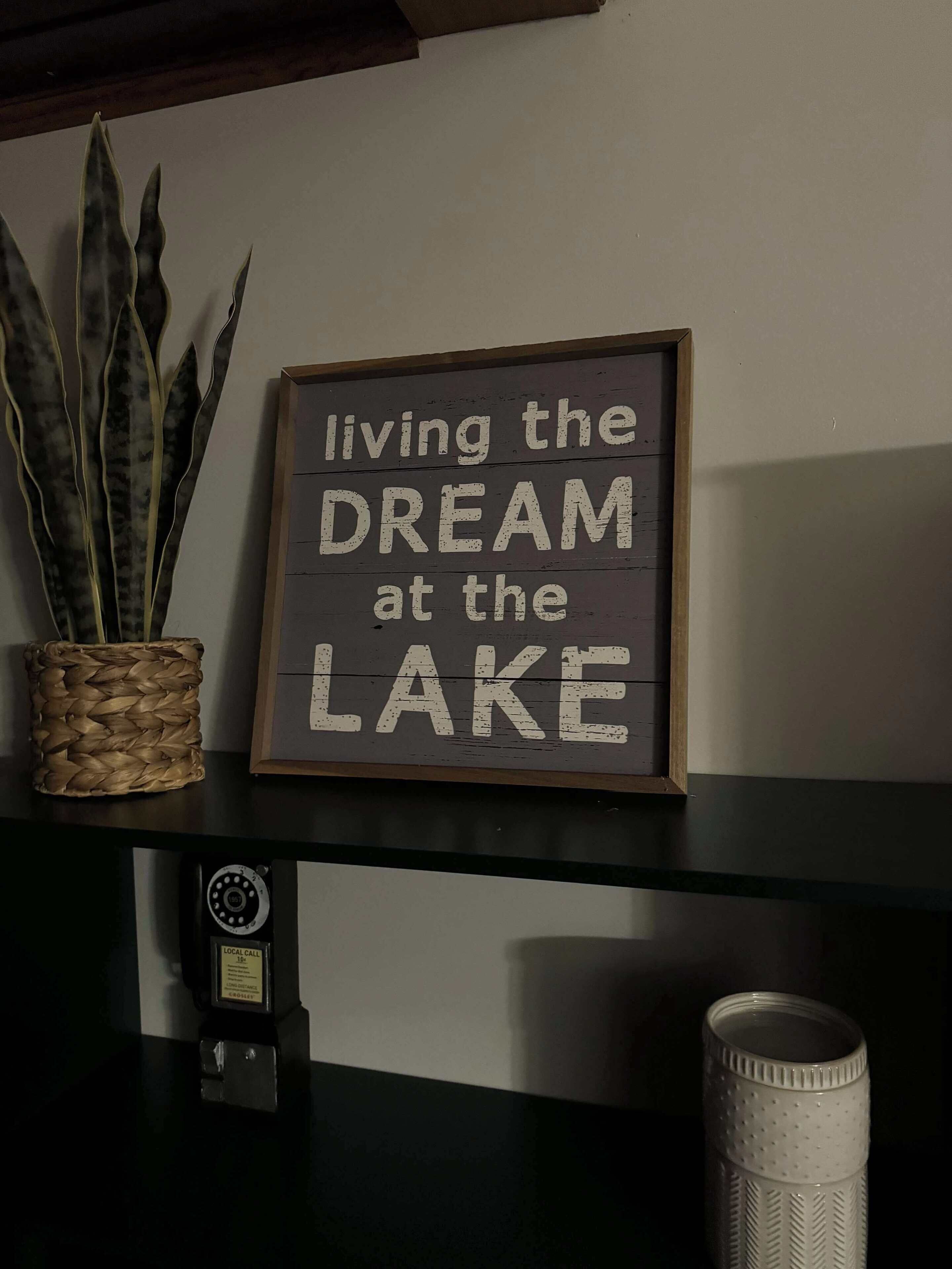 Ein Schild an einer Wand mit dem Text 'living the DREAM at the LAKE'.