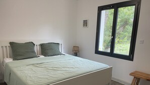Una camera da letto con un letto, due cuscini, una lampada da comodino, una finestra e una panca in legno.