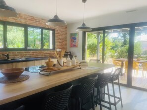 A modern kitchen with a large island, black bar stools, and a view of the outdoors.