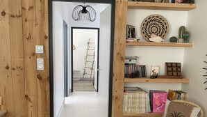 Una stanza con rivestimento in legno, una libreria, una poltrona in vimini e una scala che conduce a un'altra stanza.