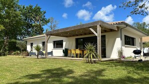 Una casa moderna con patio coperto, barbecue e prato curato.
