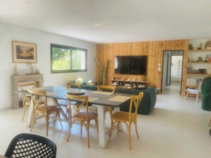 Una sala de estar moderna con comedor, paredes de paneles de madera, un televisor de pantalla plana y una chimenea.