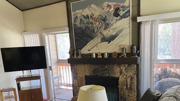 Un soggiorno con camino, un quadro appeso, una TV a schermo piatto e un divano.