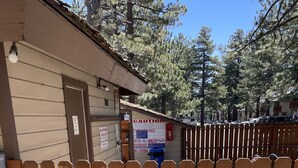 Una recinzione di legno con un cartello che indica gli orari della spa, una piscina e un edificio con una porta.