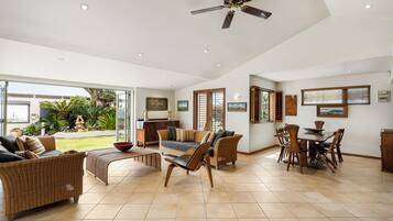 A spacious living area with a dining table, two sofas, and a ceiling fan.