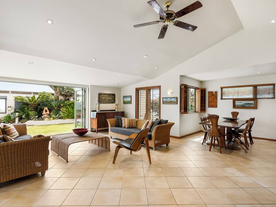 A spacious living area with a dining table, two sofas, and a ceiling fan.