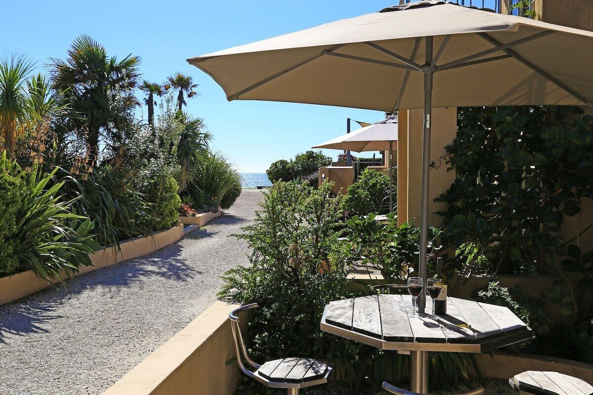 Eine Außenpatio mit Tisch und Stühlen, einem großen Sonnenschirm und Blick auf das Meer.
