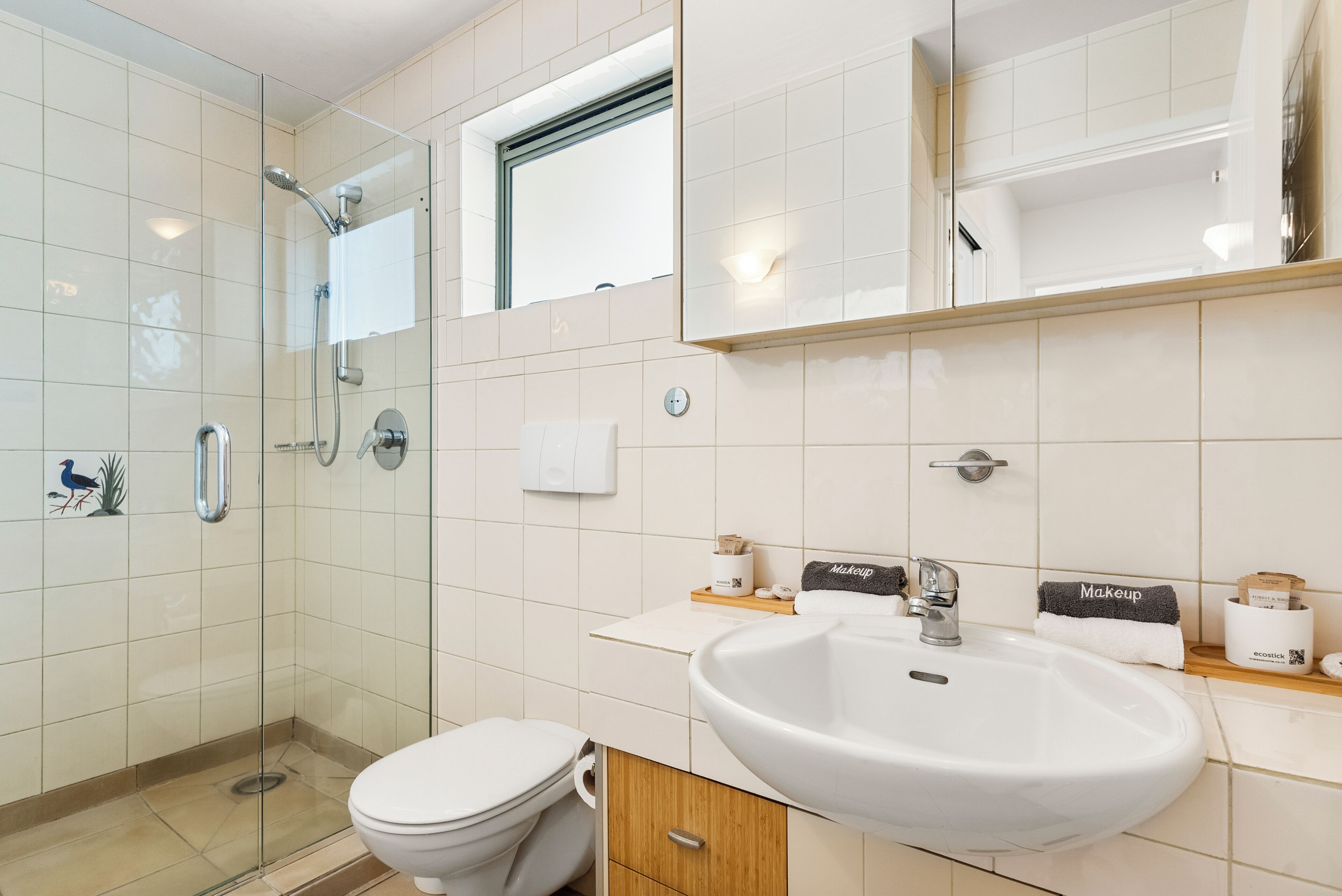 A modern bathroom with a glass-enclosed shower, a white sink, and a toilet.