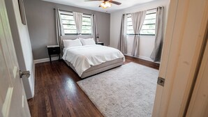 A bedroom with a bed, a ceiling fan, a nightstand, and a window with curtains. - Modern Stay on Green Valley - 2.5 mi to downtown Greensboro (Greensboro)