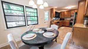 A dining area with a round table set for four, surrounded by cushioned chairs. - Modern Stay on Green Valley - 2.5 mi to downtown Greensboro (Greensboro)