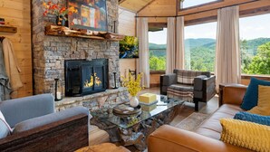 Un salon chaleureux avec une cheminée en pierre, des sièges confortables et une grande fenêtre offrant une vue panoramique.