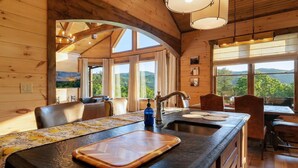L’intérieur d’un chalet en bois comprend un espace cuisine avec un grand îlot central, une table à manger et des chaises.