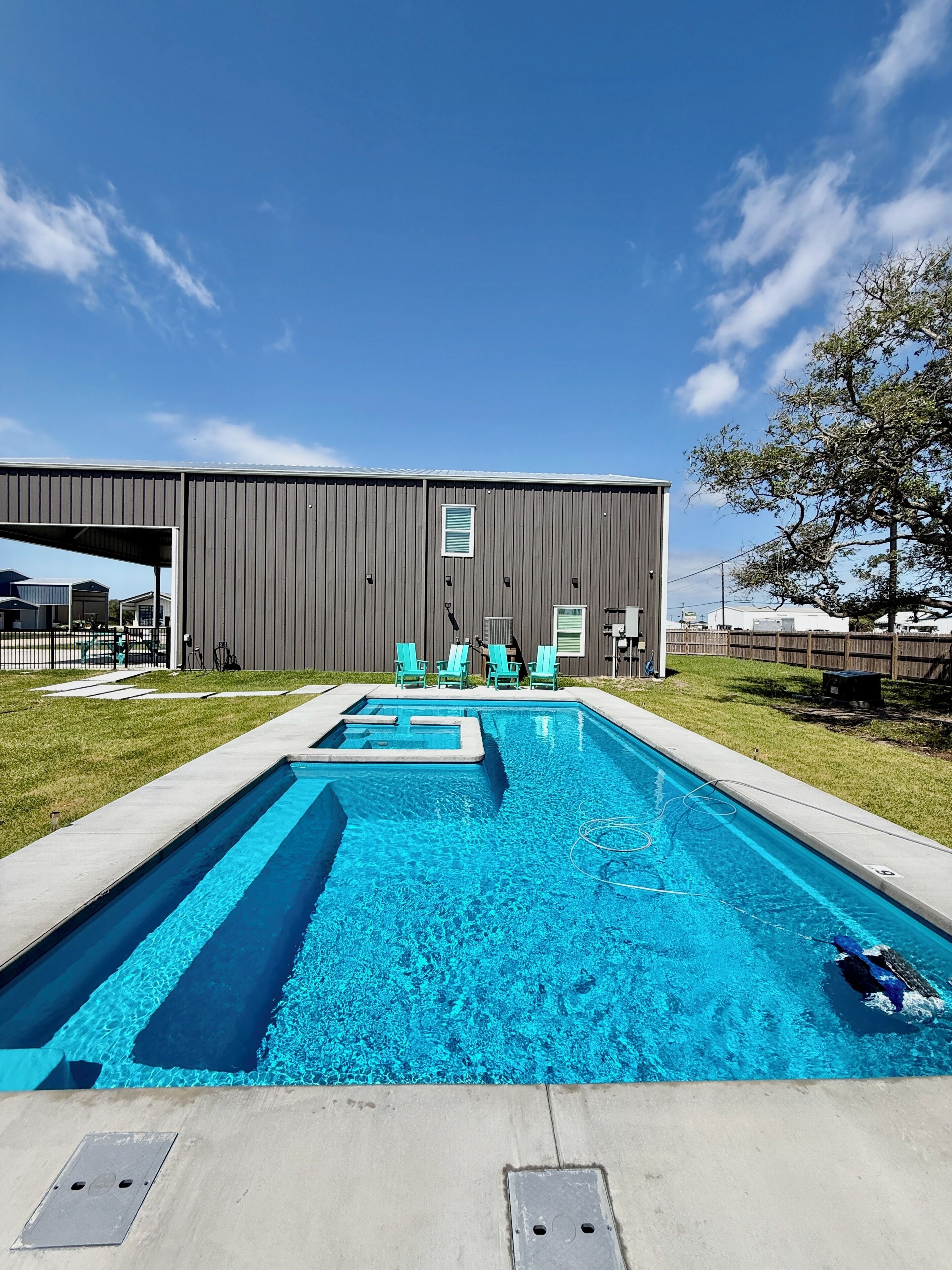A rectangular swimming pool with a clear blue water surface, surrounded by a concrete deck.