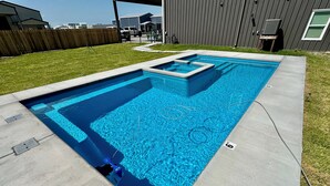 En rektangulær swimmingpool med en fastsat rutsjebane, omgivet af en betonflisebelagt terrasse.