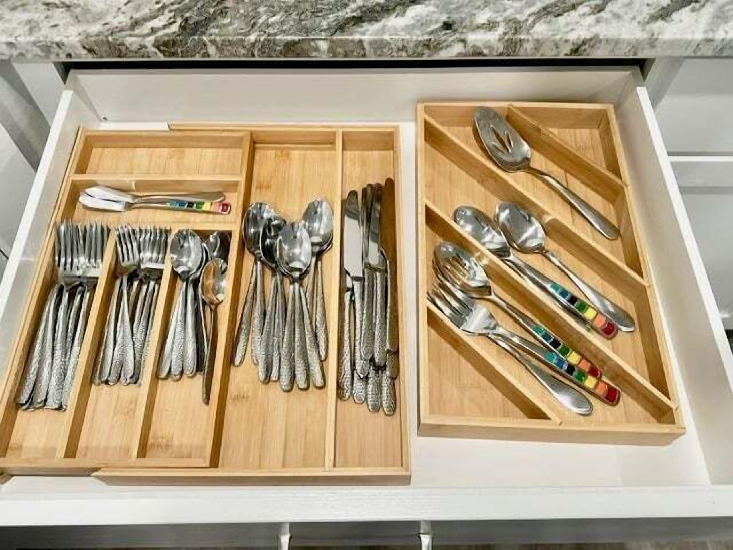 Un cajón con cubiertos ordenados, incluyendo tenedores, cucharas y cuchillos, dividido en dos compartimentos.