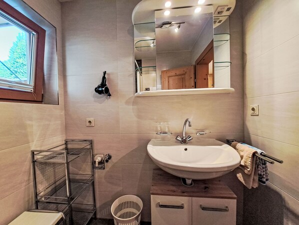 Un baño moderno con un lavamanos blanco, un espejo y una ventana.