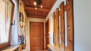 Un couloir avec des portes en bois, un banc et un radiateur.