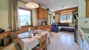 Une cuisine chaleureuse avec des meubles en bois, une table à manger dressée pour deux personnes et un canapé en arrière-plan.